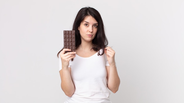 Jolie femme à la recherche de succès arrogant positif et fier et tenant une barre de chocolat