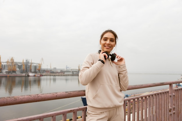 Jolie femme de remise en forme avec un casque stéréo Entraînement en plein air dans une ville industrielle