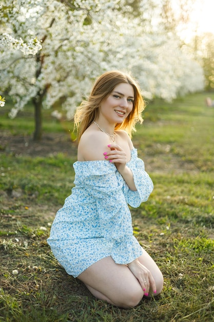 Une jolie femme en robe bleue dans un jardin printanier fleuri Une femme douce en robe d'été légère