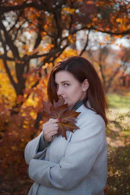 Une jolie femme rousse de bonne humeur pose un jour d'automne