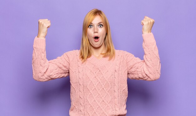 Jolie femme rousse célébrant un succès incroyable comme un gagnant, l'air excité et heureux en disant prends ça!