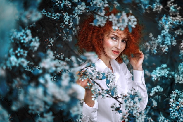 Jolie femme rousse dans un jardin fleuri