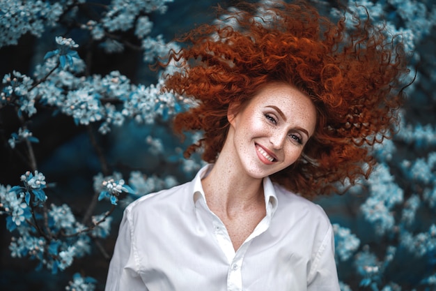 Jolie femme rousse dans un jardin fleuri