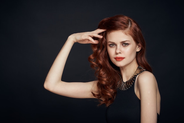 jolie femme rousse dans une robe noire coiffure fond sombre. photo de haute qualité