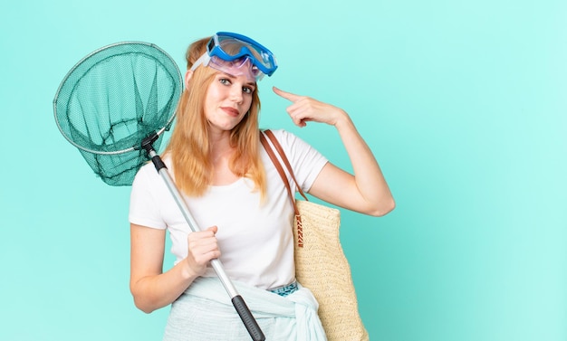 Jolie femme rousse avec un filet de pêcheur et des lunettes.