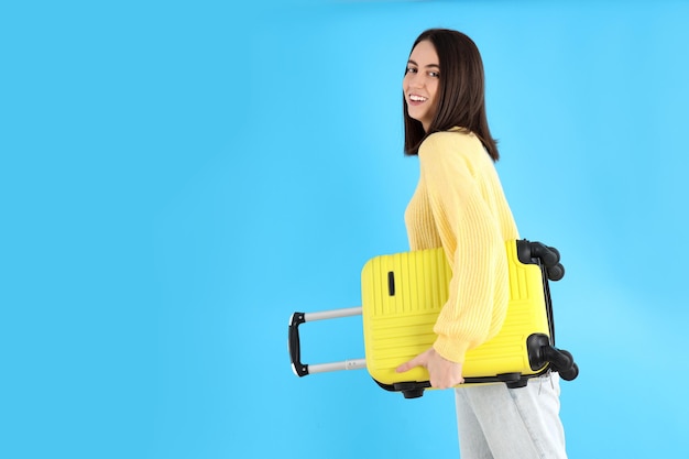 Jolie femme avec sac de voyage sur fond bleu