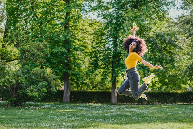 Jolie femme sautant joyeusement dans un jardin. Vue de côté. Tout le corps.