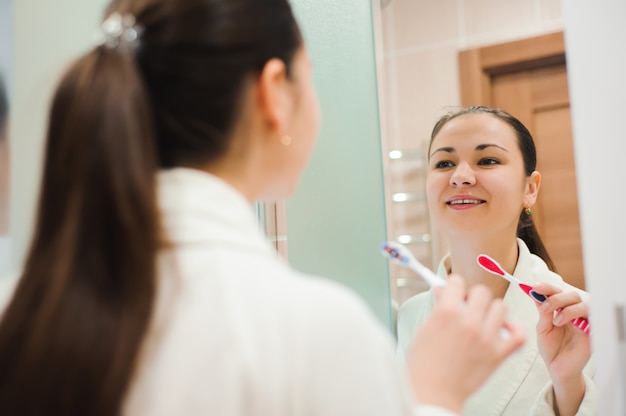 Jolie femme se brosser les dents devant le miroir