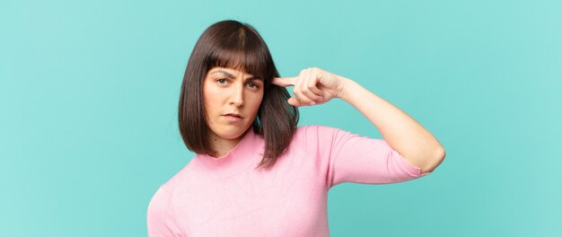 Jolie femme se sentant confuse et perplexe, montrant que vous êtes fou, fou ou fou