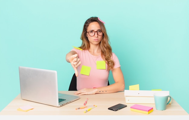 Jolie femme se sentant croisée, montrant les pouces vers le bas. concept de télétravail