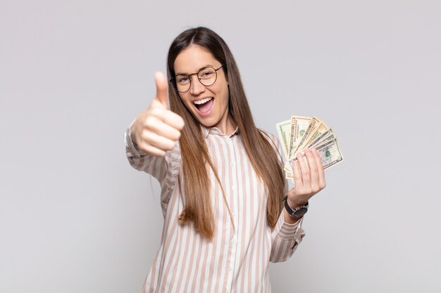 Jolie femme se sentant fière, insouciante, confiante et heureuse, souriant positivement avec les pouces vers le haut