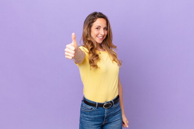 Jolie femme se sentant fière, souriante positivement avec le pouce levé