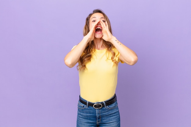 Jolie femme se sentant heureuse, donnant un grand cri avec les mains à côté de la bouche