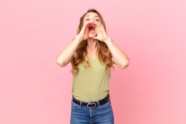 Jolie femme se sentant heureuse, donnant un grand cri avec les mains à côté de la bouche