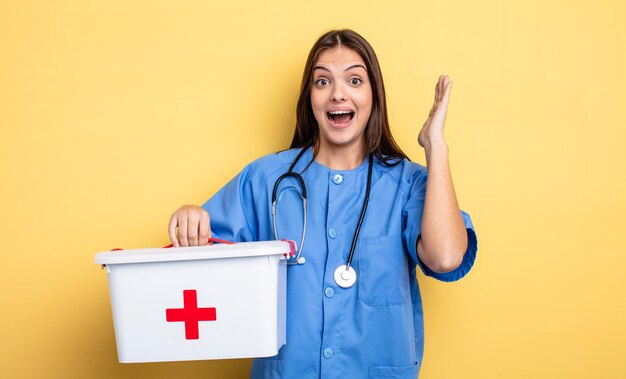 Jolie femme se sentant heureuse et étonnée de quelque chose d'incroyable. infirmière avec une trousse de premiers soins infirmière