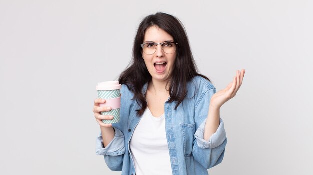 Jolie femme se sentant heureuse et étonnée de quelque chose d'incroyable et tenant un café à emporter