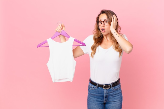 Jolie femme se sentant heureuse, excitée et surprise et choisissant des vêtements