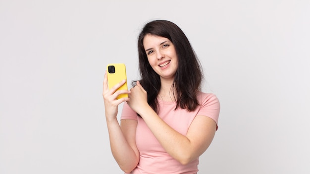 Jolie femme se sentant heureuse et faisant face à un défi ou célébrant à l'aide d'un téléphone intelligent