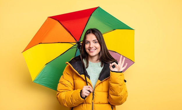 jolie femme se sentant heureuse, montrant son approbation avec un geste correct. concept hiver et parapluie