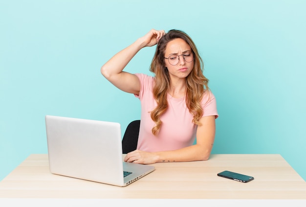 Jolie femme se sentant perplexe et confuse, se grattant la tête. concept de télétravail