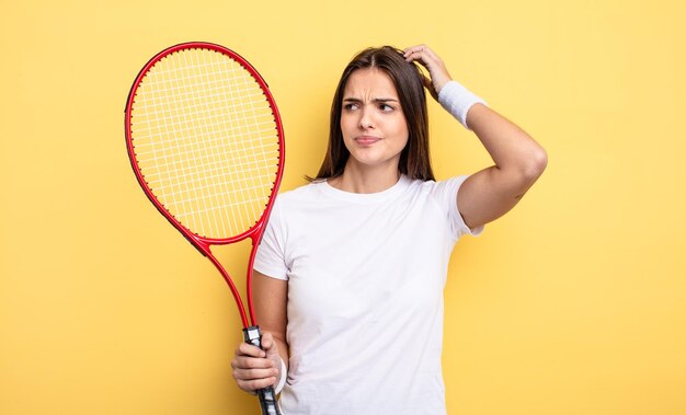 Jolie femme se sentant perplexe et confuse, se grattant la tête. notion de joueur de tennis