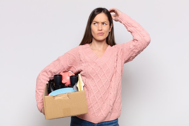 Jolie femme se sentant perplexe et confuse, se grattant la tête et regardant sur le côté