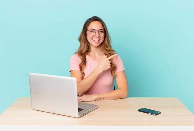 Jolie femme semblant excitée et surprise en pointant sur le côté. concept de télétravail