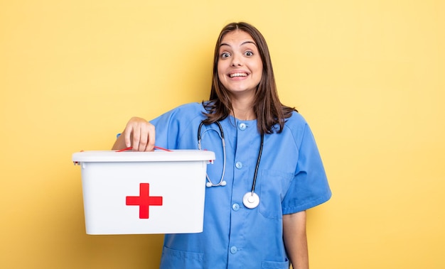 Jolie femme semblant heureuse et agréablement surprise. infirmière avec une trousse de premiers soins infirmière