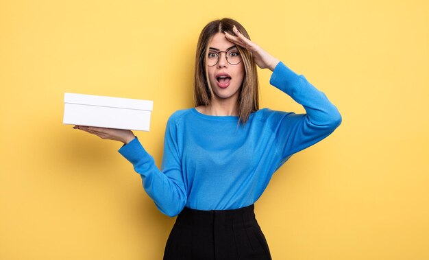 jolie femme semblant heureuse, étonnée et surprise. tenant une boîte blanche