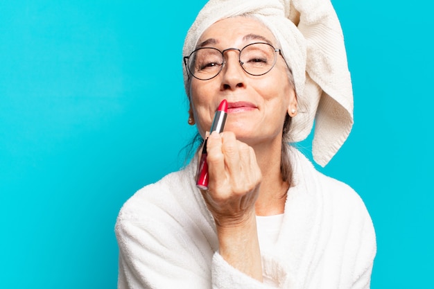 Jolie femme senior après la douche maquillant et portant un peignoir