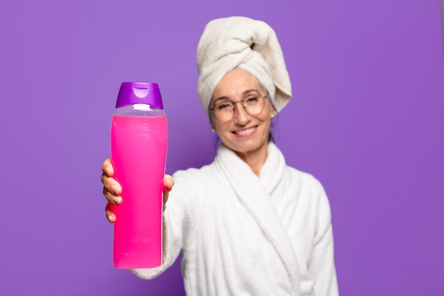 Jolie femme senior après la douche en peignoir. concept de produits de nettoyage du visage ou de douche