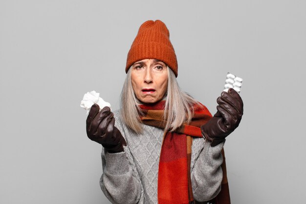 jolie femme senior avec une tablette de pilules portant des vêtements d'hiver. notion de grippe