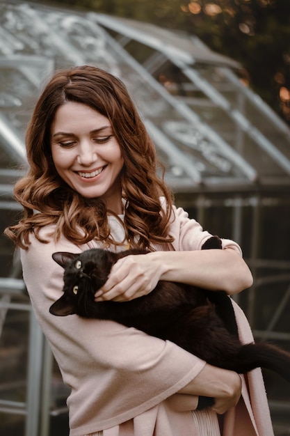 Jolie femme à son s dans le jardin avec chat noir