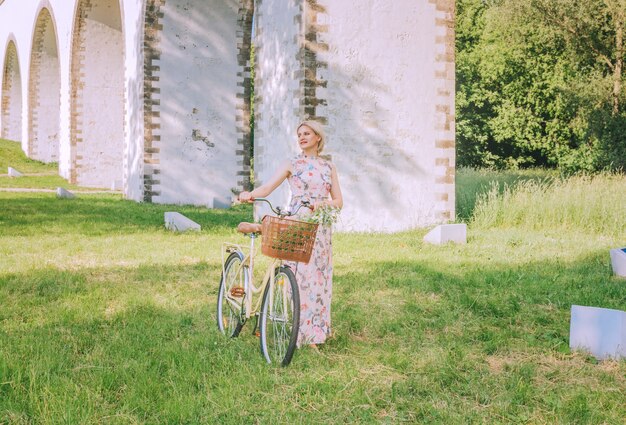 Jolie femme avec son vélo sur le fond de l'aqueduc du pont en saison estivale.