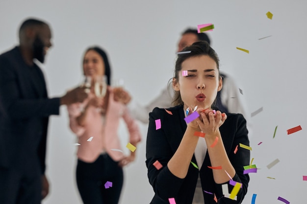 La jolie femme soufflant des confettis