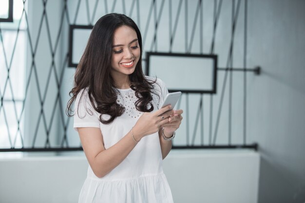 Jolie femme souriante à l'aide de téléphone intelligent