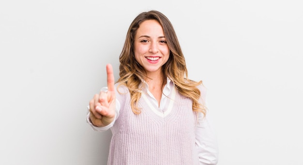 Jolie femme souriante et amicale montrant le numéro un ou le premier avec la main en avant compte à rebours