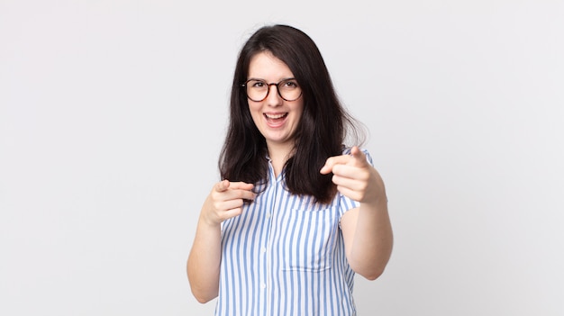 jolie femme souriante avec une attitude positive, réussie et heureuse pointant vers la caméra, faisant un signe d'arme avec les mains