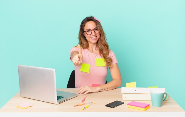 Jolie femme souriante fièrement et en toute confiance faisant numéro un. concept de télétravail