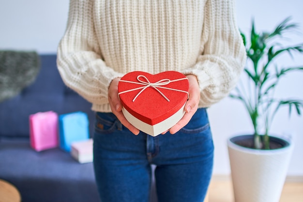 Jolie Femme Souriante Heureuse Charmante Bien-aimée A Reçu Un Cadeau Pour La Saint-valentin Et Ouvre Une Boîte En Forme De Coeur Pour La Saint-valentin