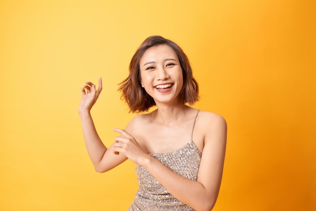 Jolie femme souriante heureuse en robe scintillante avec danse célébrant Noël et le nouvel an