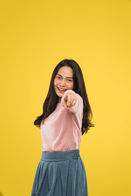 Jolie femme souriante joyeusement avec une main pointée vers l'avant