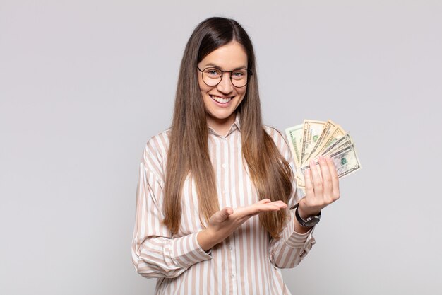 Jolie femme souriante joyeusement, se sentant heureuse et montrant un concept dans l'espace de copie avec la paume de la main