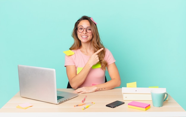 Jolie femme souriante joyeusement, se sentant heureuse et pointant sur le côté. concept de télétravail