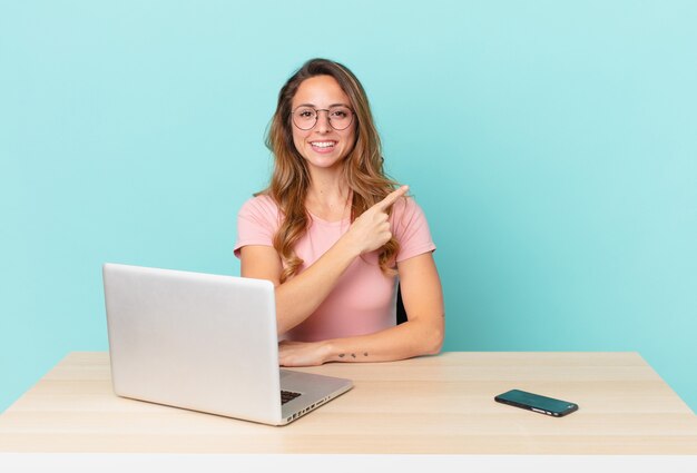 Jolie femme souriante joyeusement, se sentant heureuse et pointant sur le côté. concept de télétravail