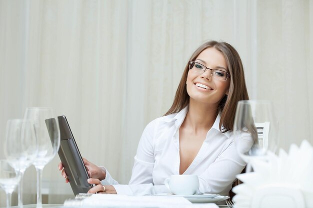 Jolie femme souriante à lunettes travaille sur ordinateur portable