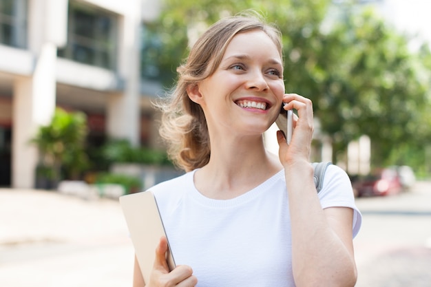 Jolie femme souriante, parler au téléphone à l&#39;extérieur