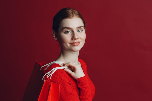 Jolie femme souriante portrait avec des sacs à provisions en papier rouge Vendredi noir et concept de vente