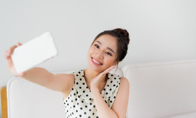 Jolie femme souriante prenant un selfie à l'aide d'un smartphone.