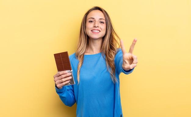 Jolie femme souriante et regardant heureuse gesticulant victoire ou concept de chocolat de paix